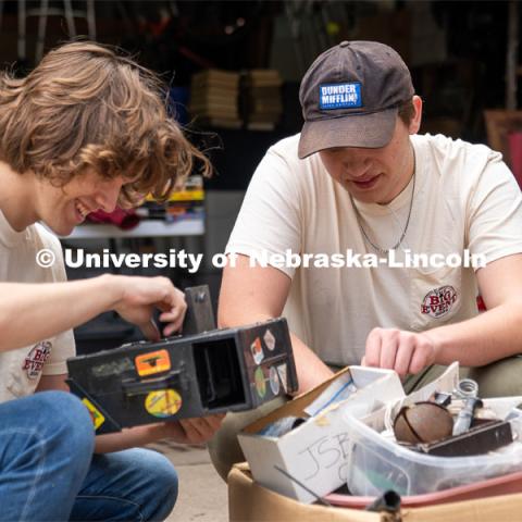 Phi Kappa Theta members Ryan Richter (left) and Isaac Alfieri (right) look through a box of antique trinkets and miscellaneous items during the Big Event. May 4, 2024. Photo by Kirk Rangel for University Communication.